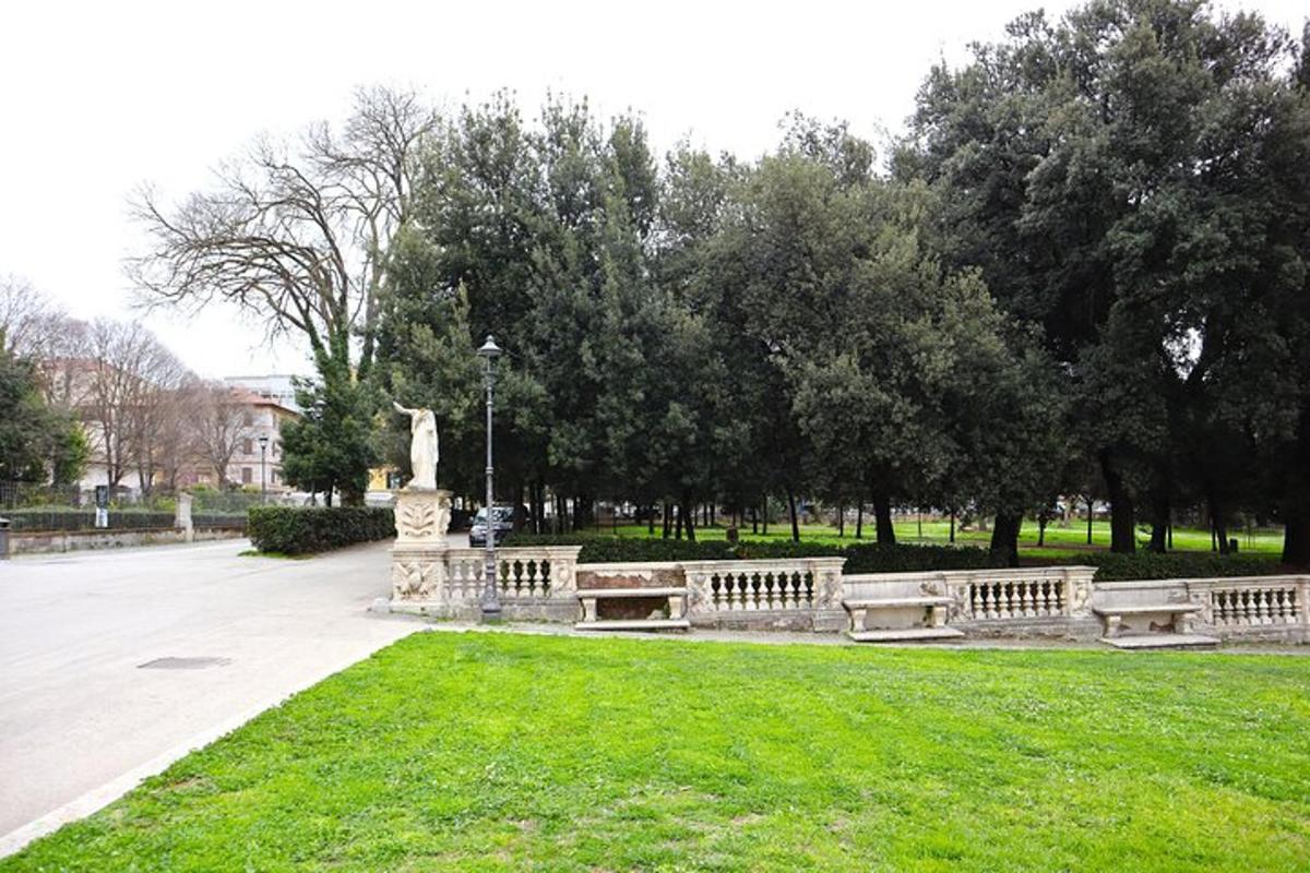 egy park padokkal és egy szoborral a fűben