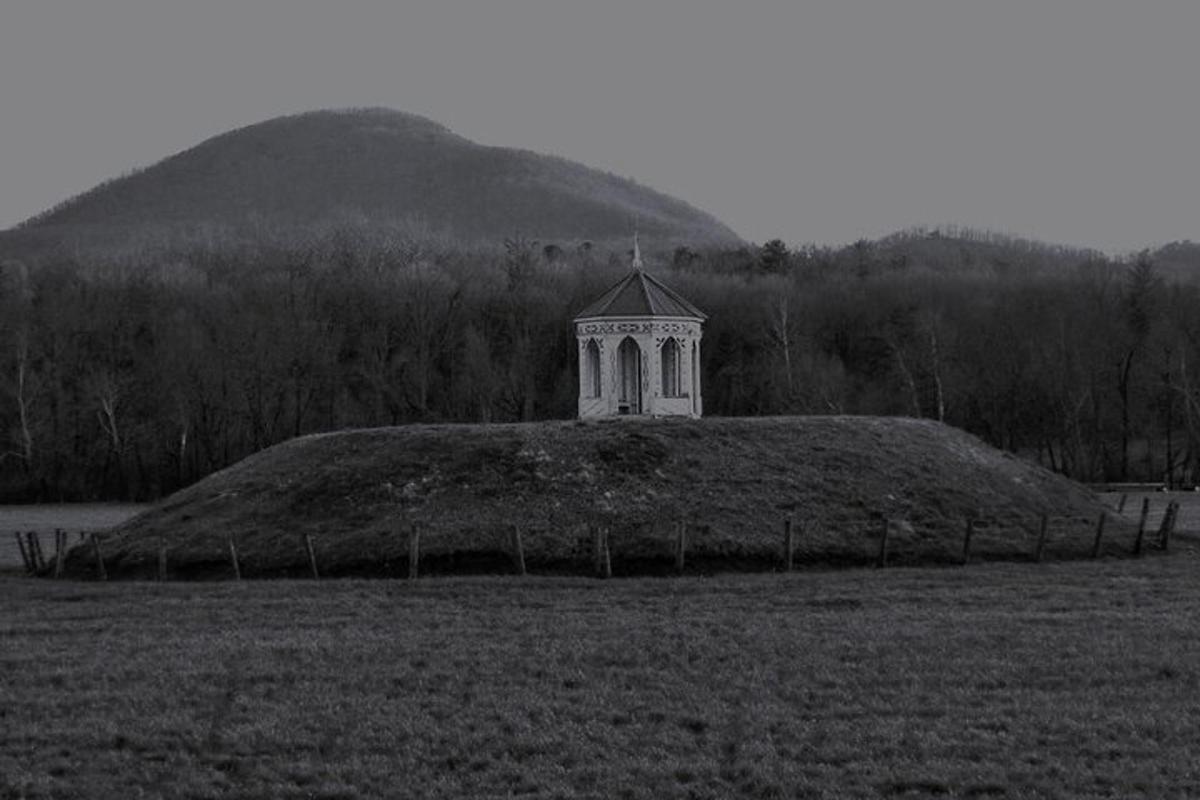a large hill with a tower on top of it in a field