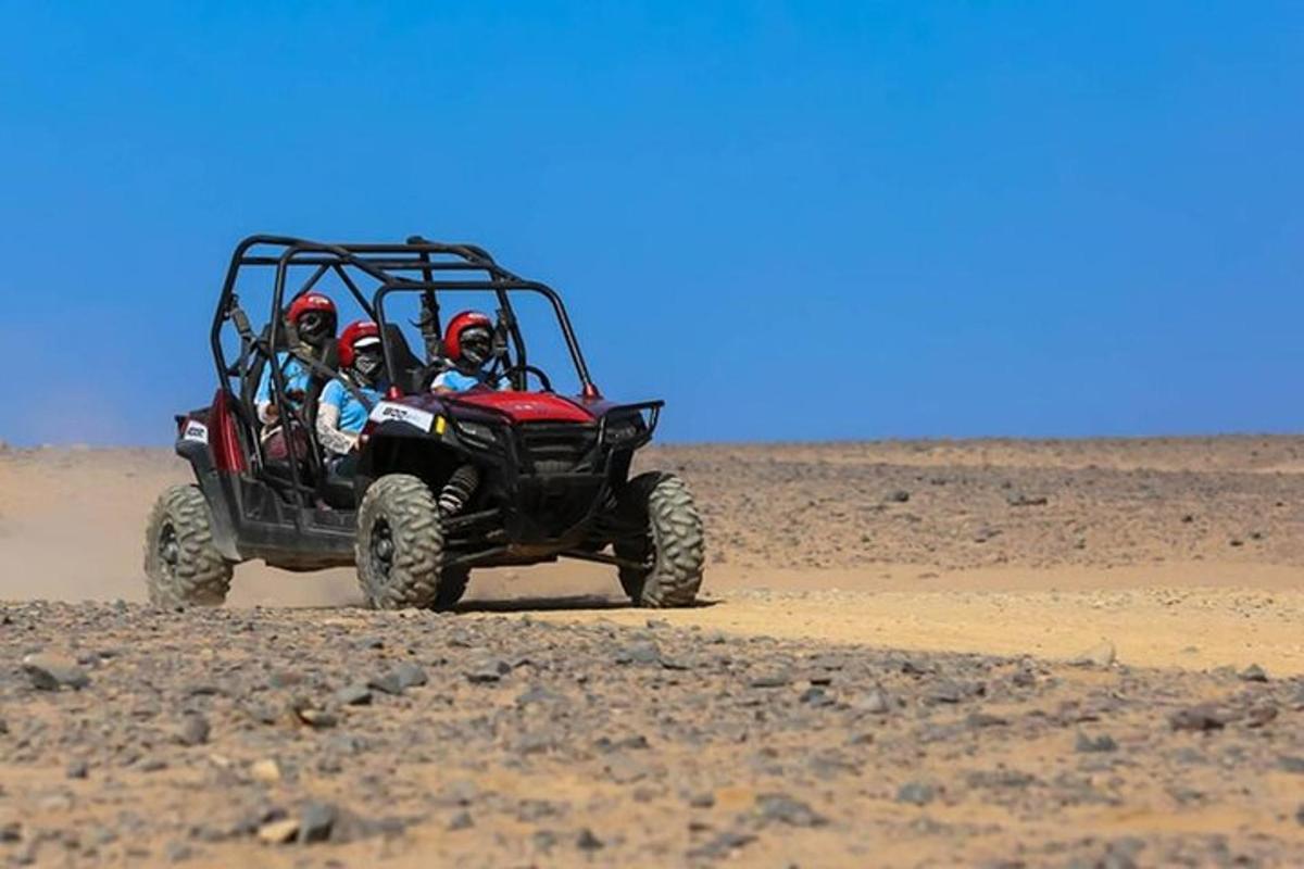 duas pessoas andando em um quadriciclo no deserto