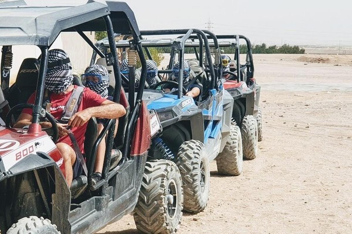 um grupo de pessoas andando em quatro quadriciclos na praia