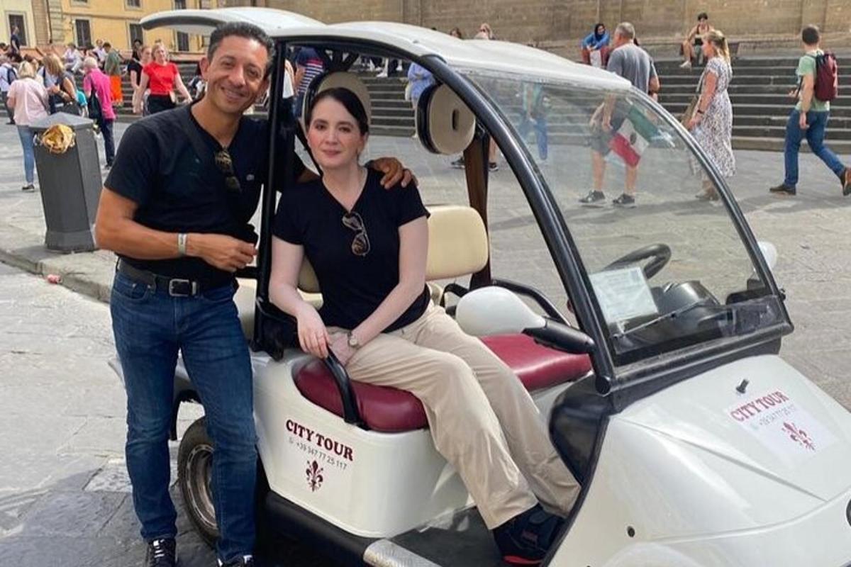 um homem e uma mulher sentados em um carrinho de golfe