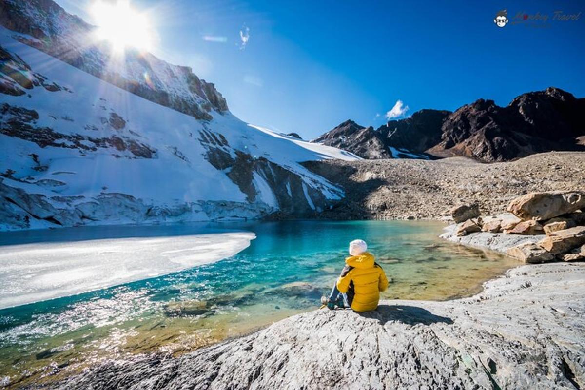 a person sitting on a rock next to a lake