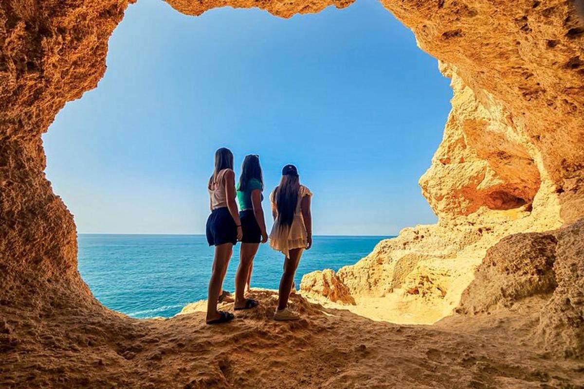 tre ragazze in piedi in una grotta che guardano l'oceano