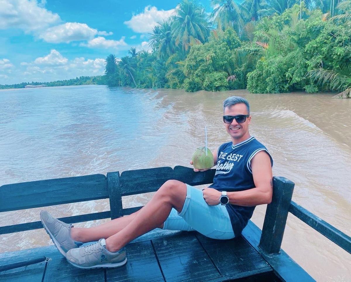 a man sitting on a bench next to a river