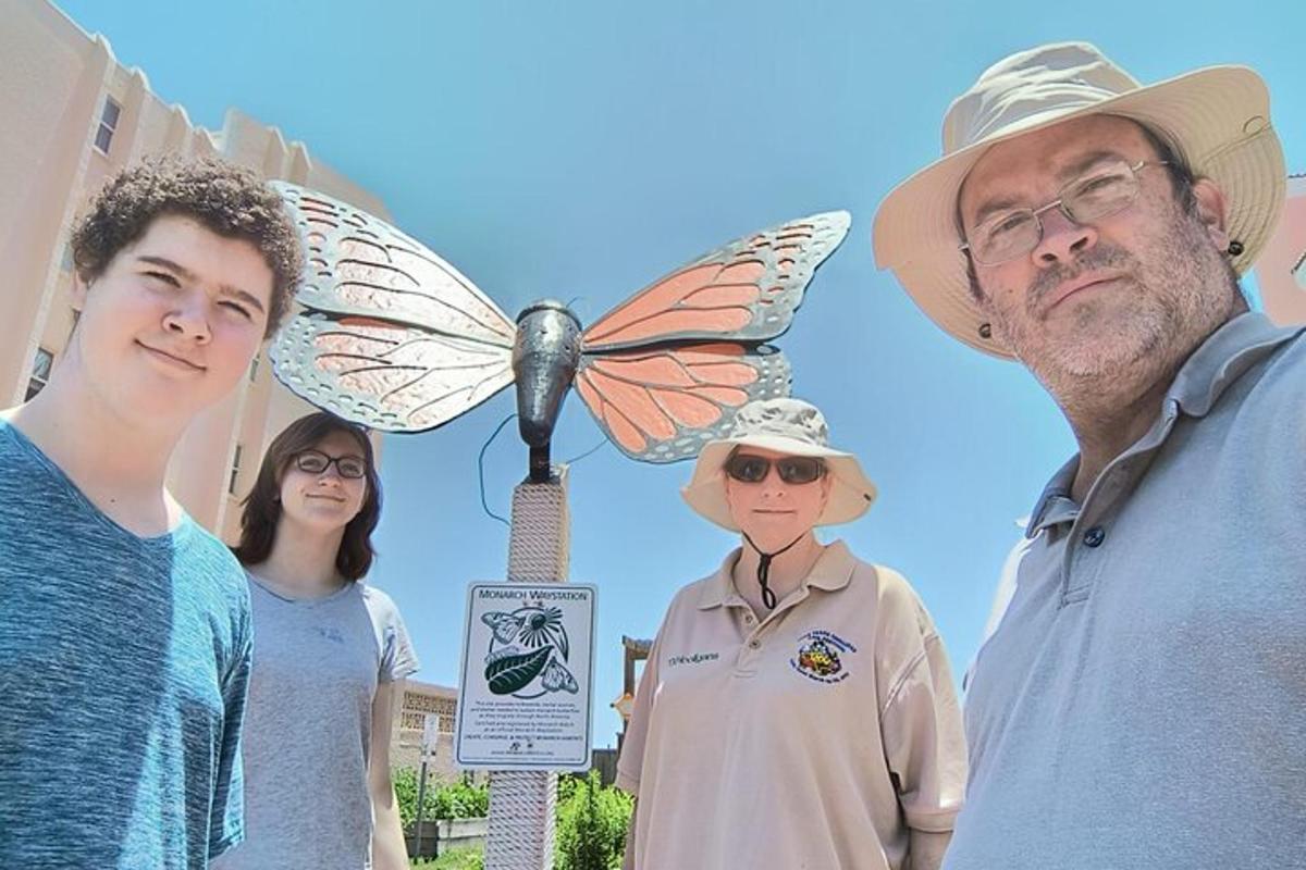 a group of people standing next to a butterfly statue