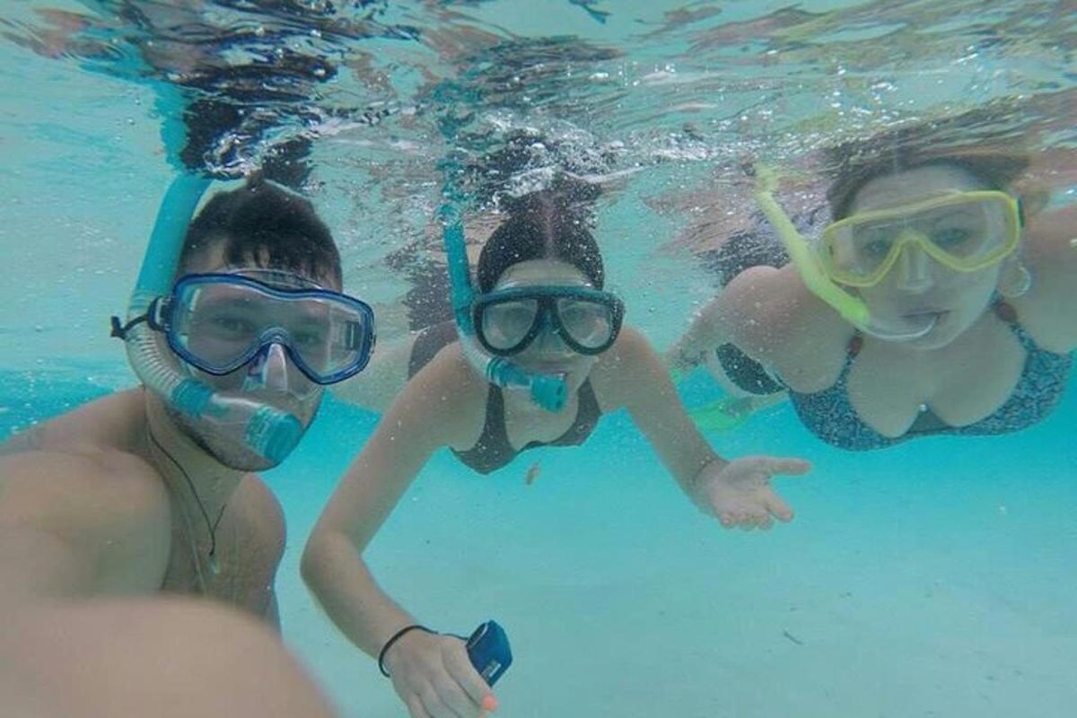 un gruppo di tre persone che indossano occhialini e nuotano nell'acqua