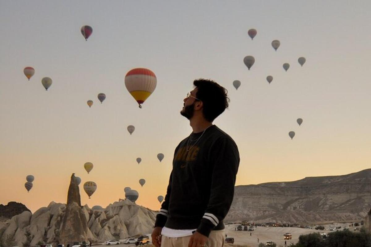 a man standing in front of a bunch of hot air balloons
