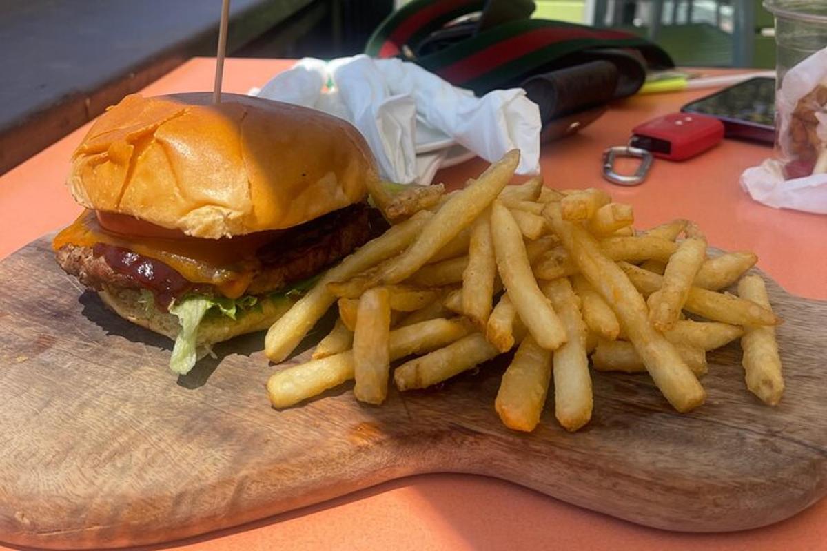 um hambúrguer e batatas fritas em uma tábua de corte de madeira