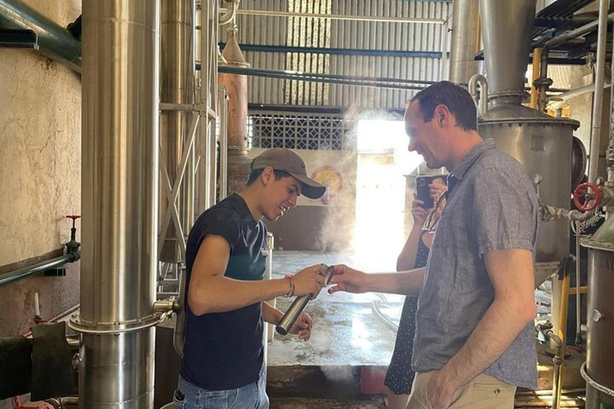 Dos hombres de pie en una fábrica trabajando en algo.