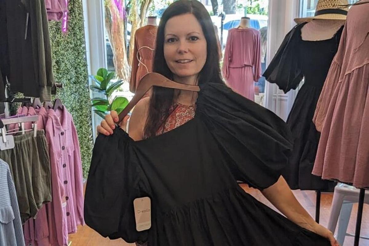 a woman is holding a dress in a clothing store