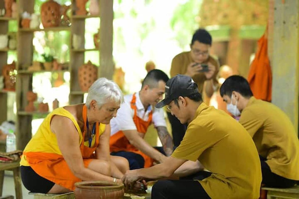 a group of people standing around a woman preparing food