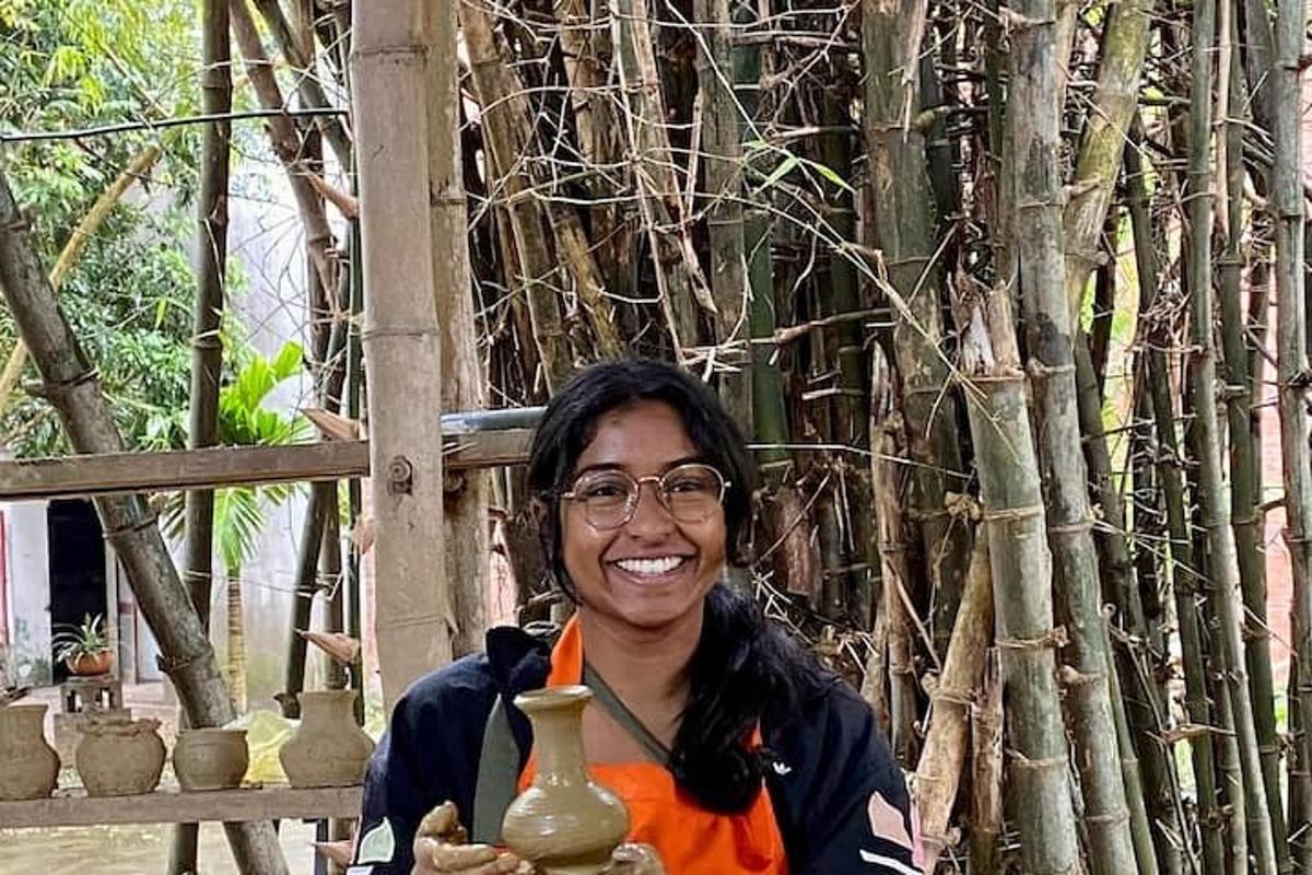 a woman holding vases in front of a tree