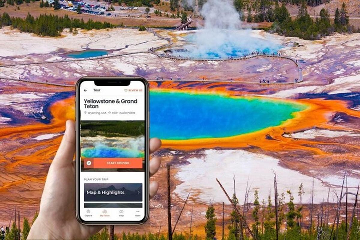 a hand holding a cell phone in front of a geyser
