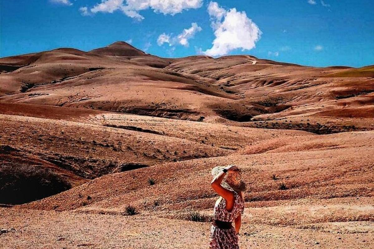 a woman standing in the desert looking at a mountain