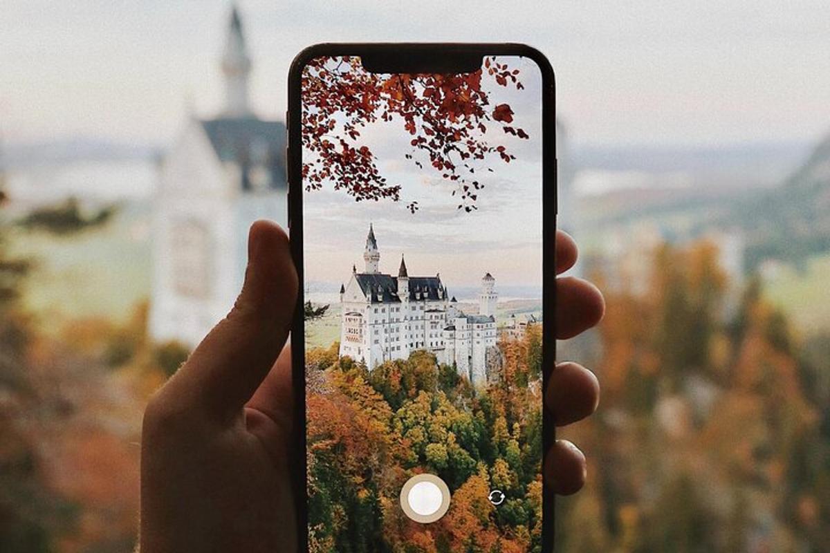 osoba držiaca mobilný telefón a fotiaca hrad