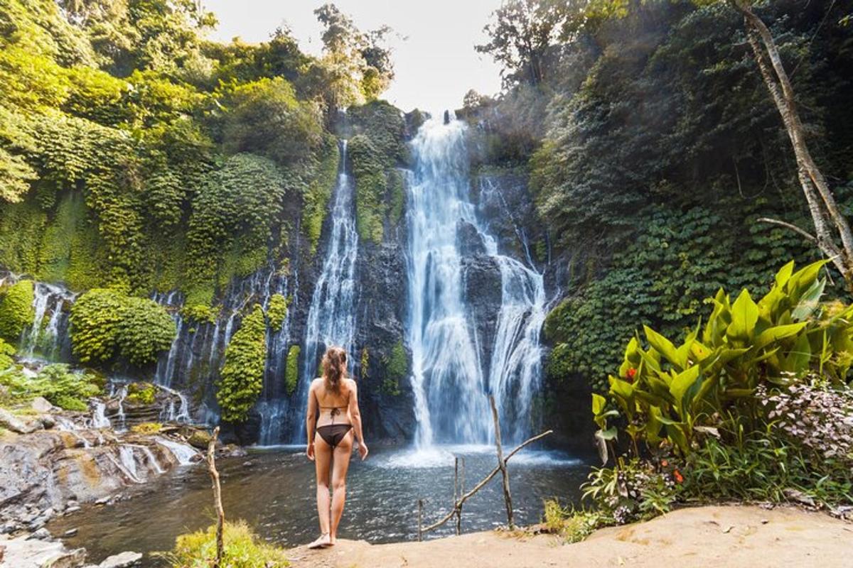 seorang wanita berjalan di dalam air di hadapan air terjun