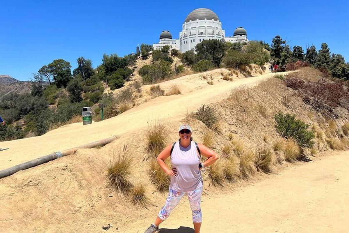 seorang lelaki berdiri di atas bukit di hadapan sebuah bangunan