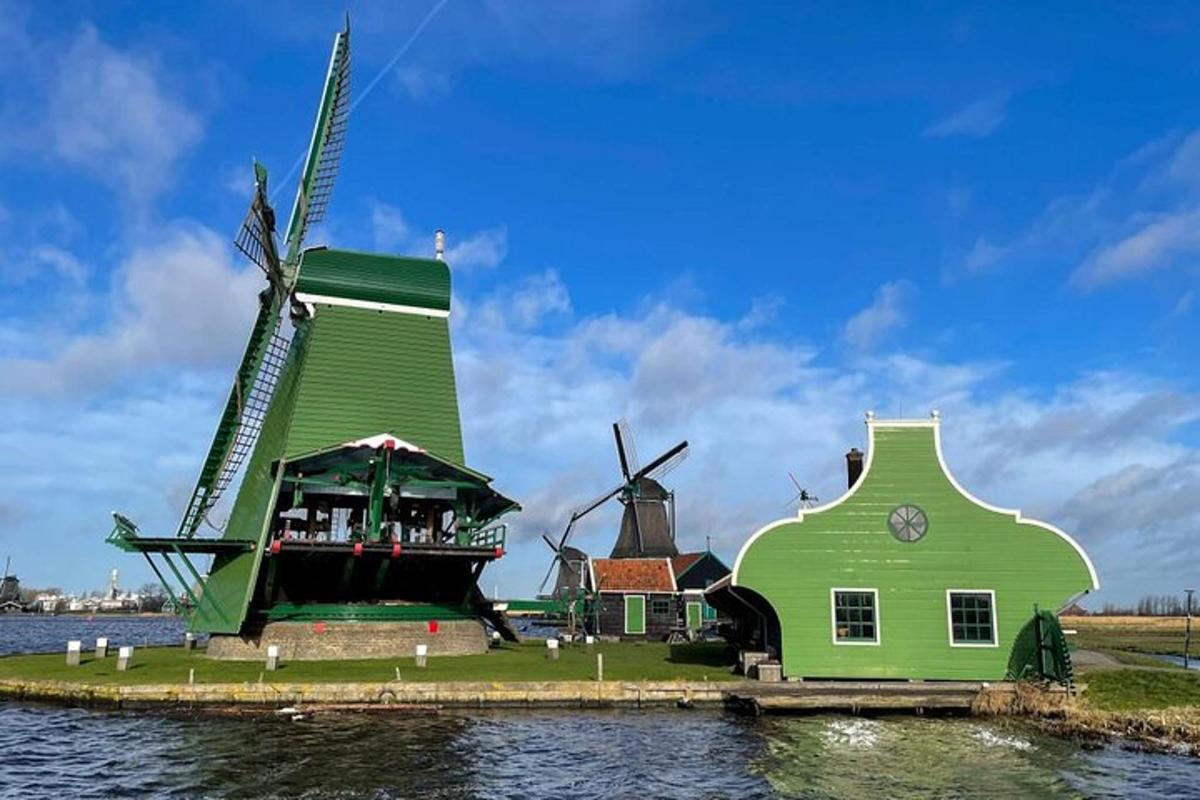 Un edificio verde y un molino de viento en el agua.