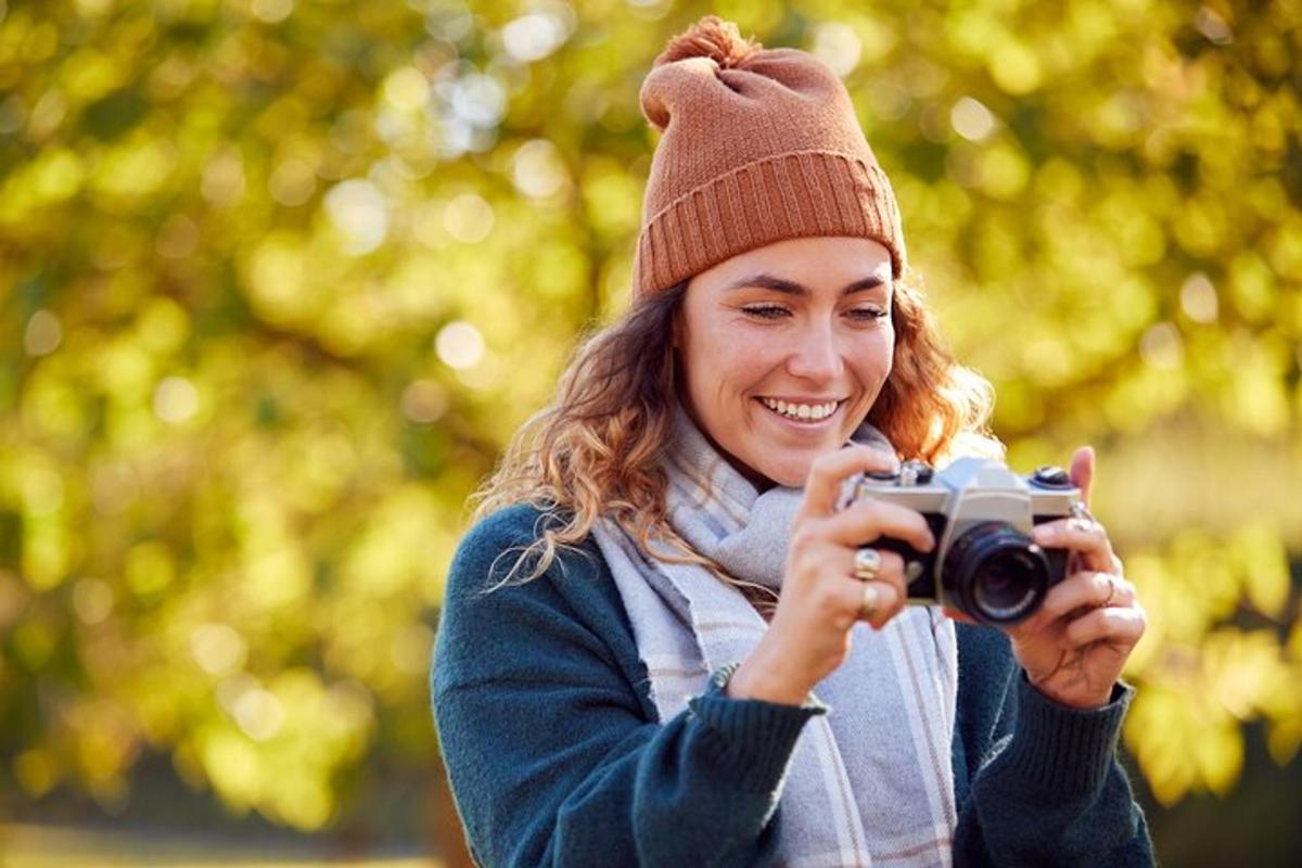 Una mujer con sombrero tomando una foto con una cámara.