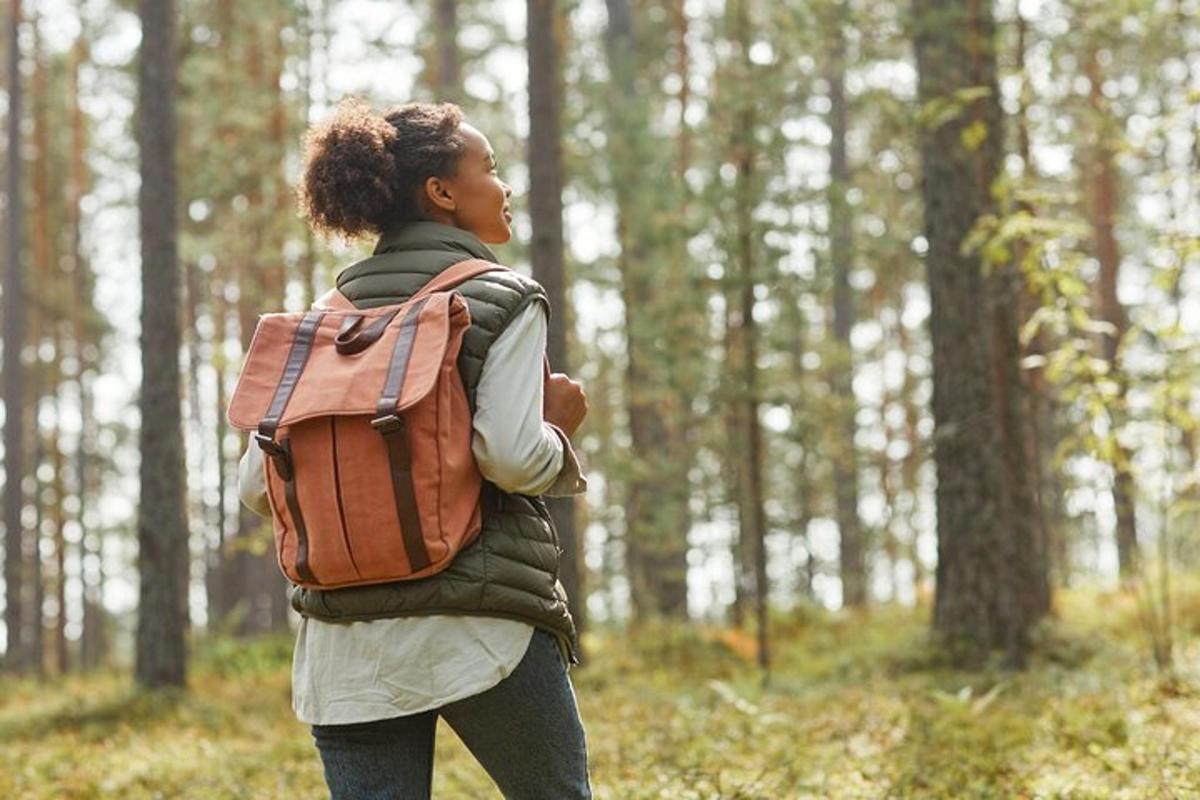 o femeie cu un rucsac mergând printr-o pădure