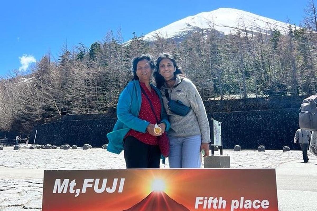 due donne in piedi dietro un cartello con una montagna sullo sfondo