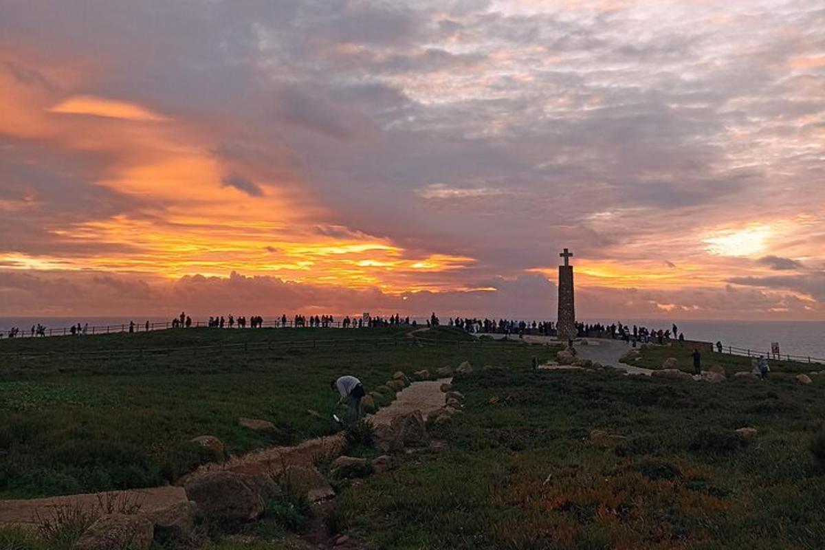 un gruppo di persone in piedi attorno a un faro al tramonto