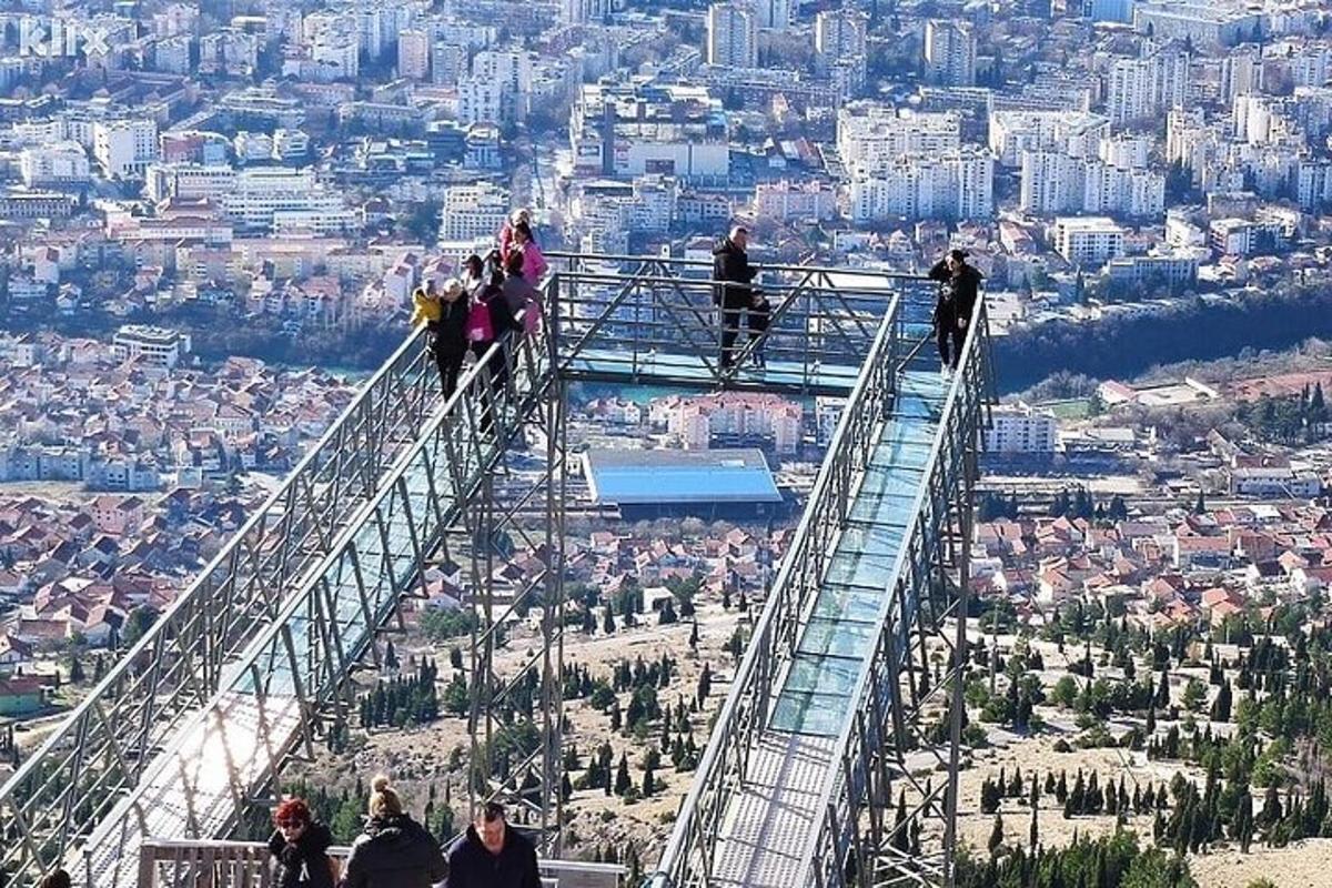 un grup de persones dretes en una passarel·la de vidre a la part superior d'un mirador