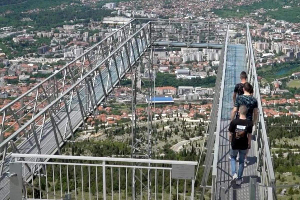 dues persones caminant per un pont penjant sobre una ciutat