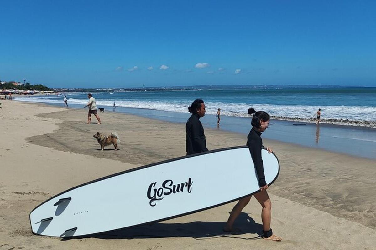two people walking on the beach with a surfboard