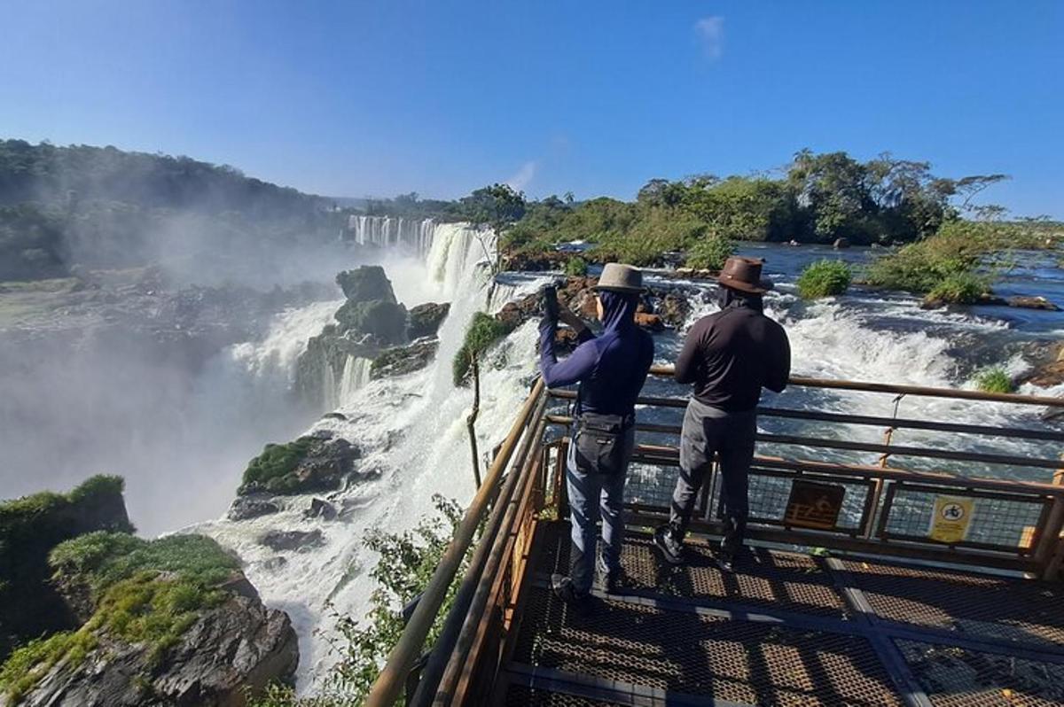 zwei Männer stehen auf einer Aussichtsplattform und schauen auf einen Wasserfall