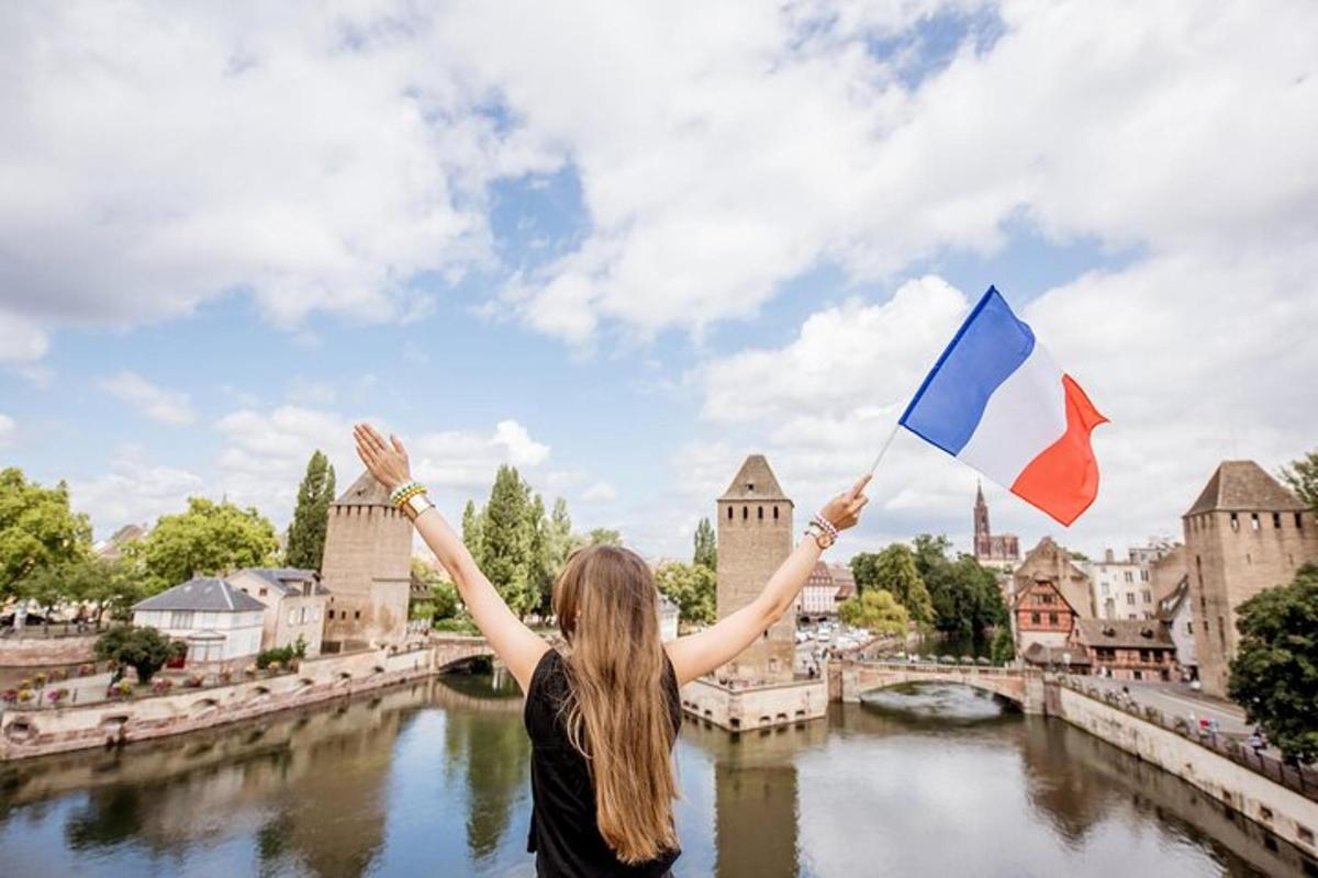 o femeie care ține un steag francez și italian în fața unui castel