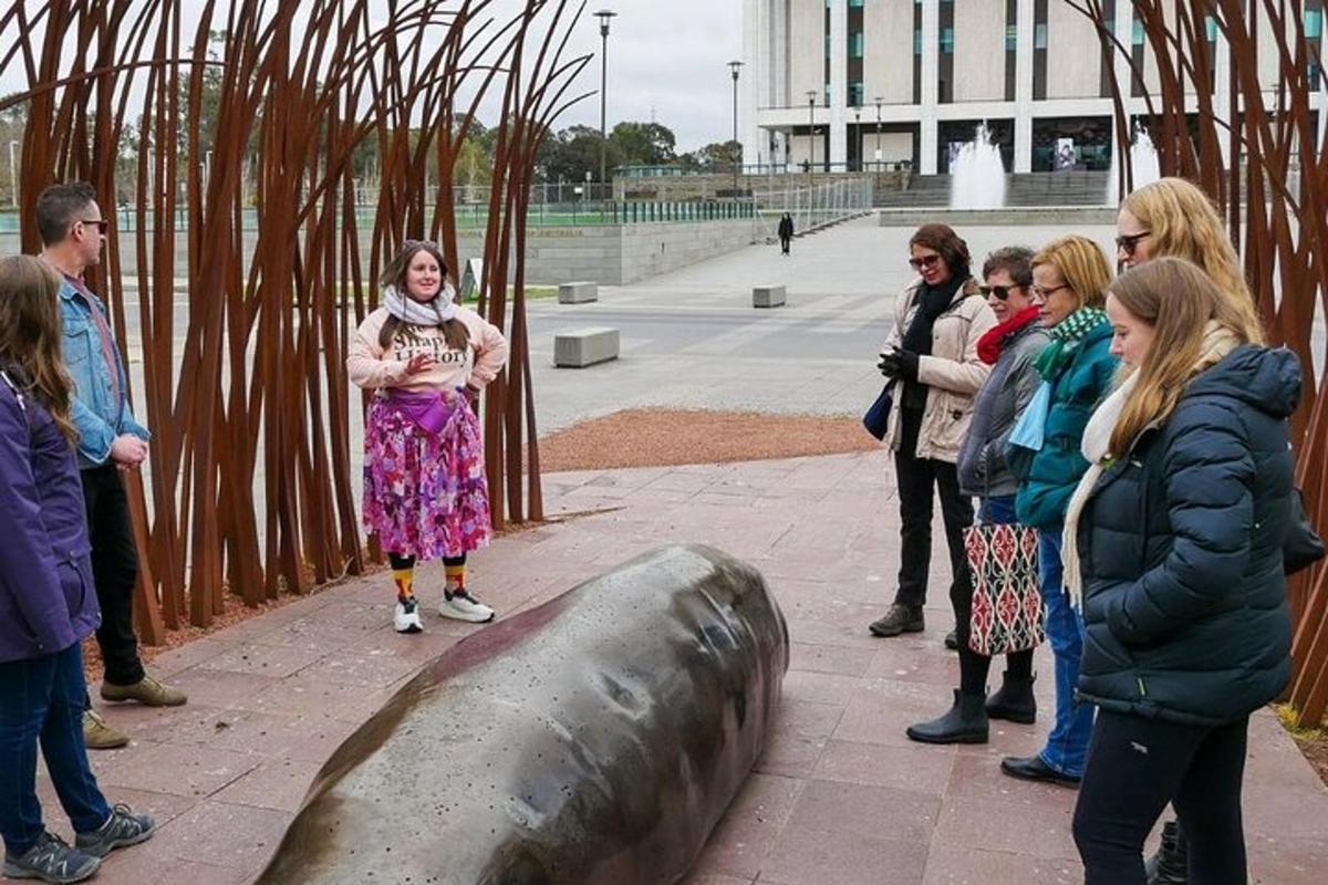 a group of people standing around a metal whale