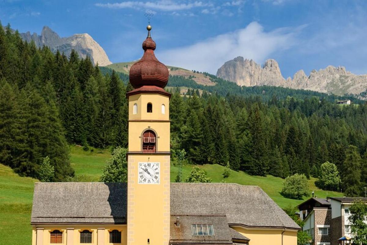 un edificio con una torre dell'orologio e montagne sullo sfondo
