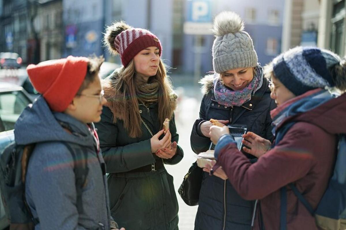 un gruppo di persone in piedi per strada che guardano i loro cellulari