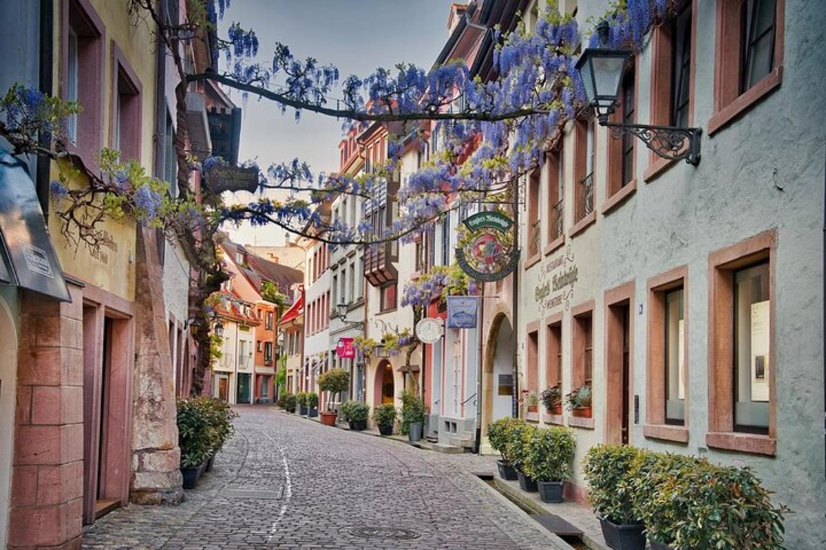 a narrow street with flowers hanging from buildings