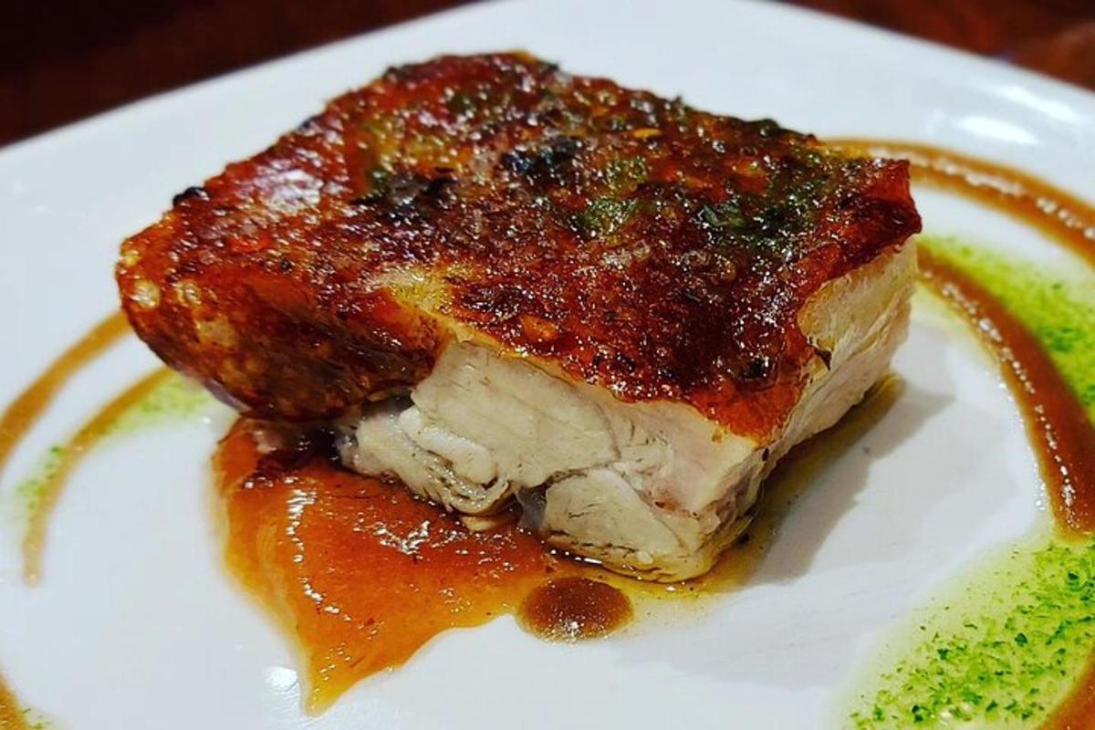 a piece of meat on a white plate with sauce