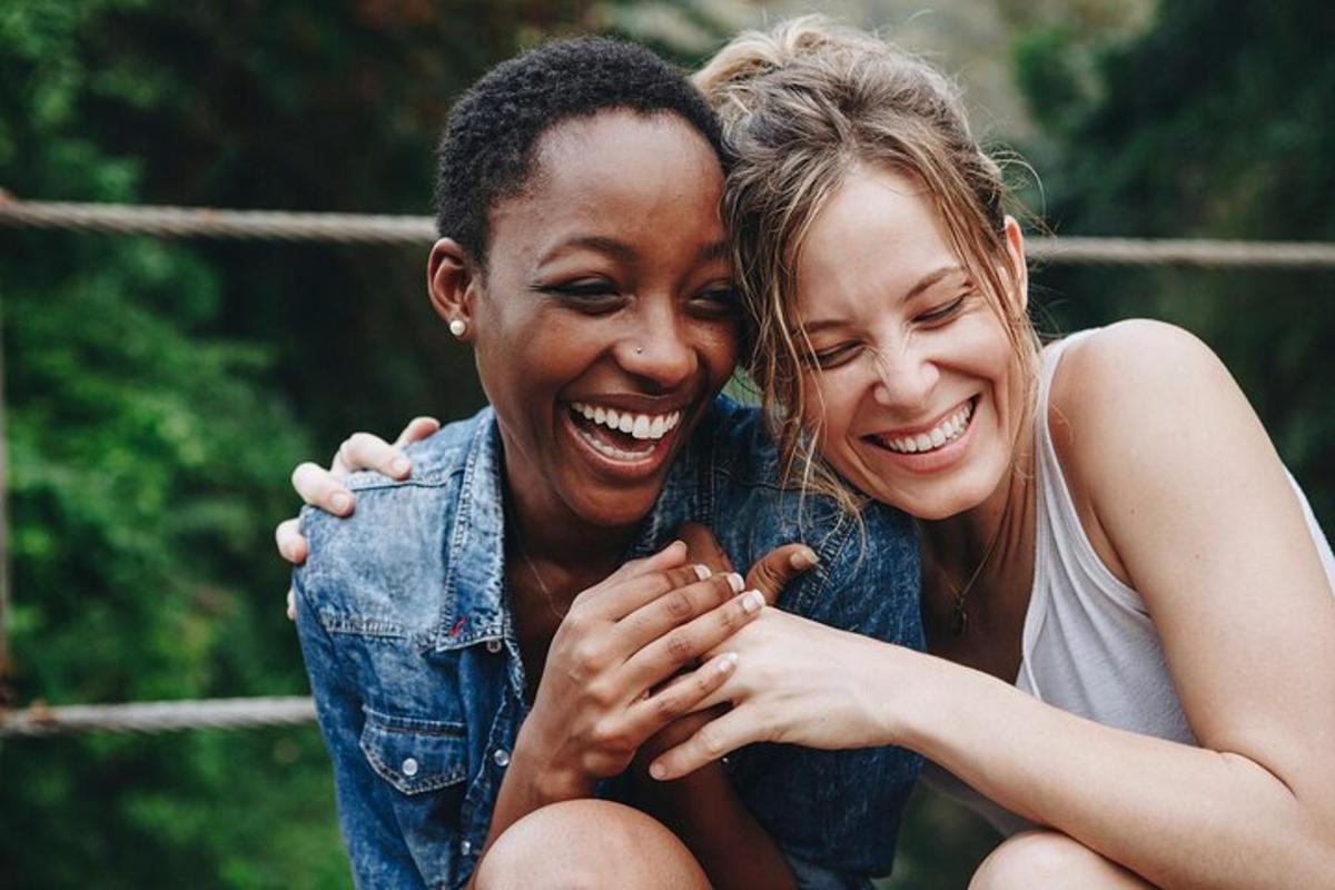 duas mulheres rindo enquanto se abraçam