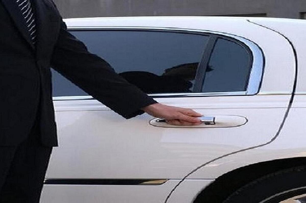 um homem de terno destrancando a porta de um carro branco