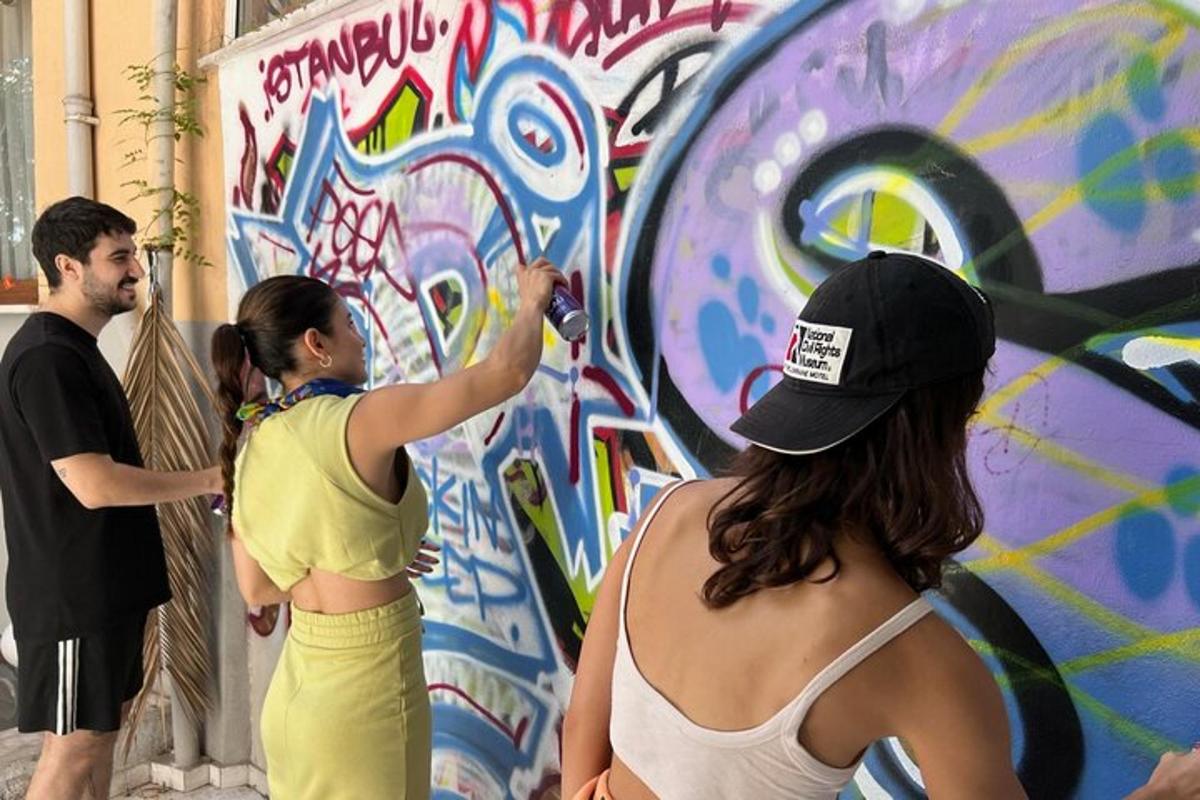 een paar mensen die een muur beschilderen met graffiti