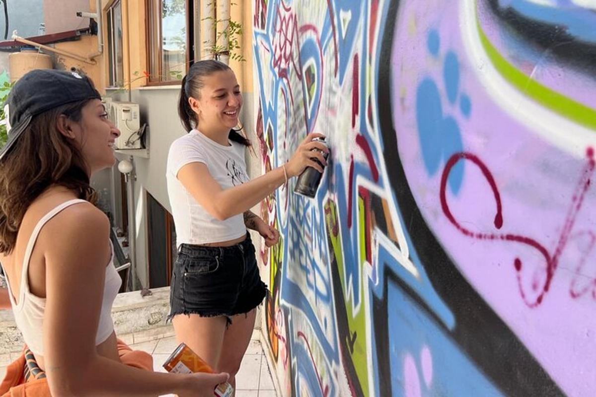 two girls are painting a wall with graffiti