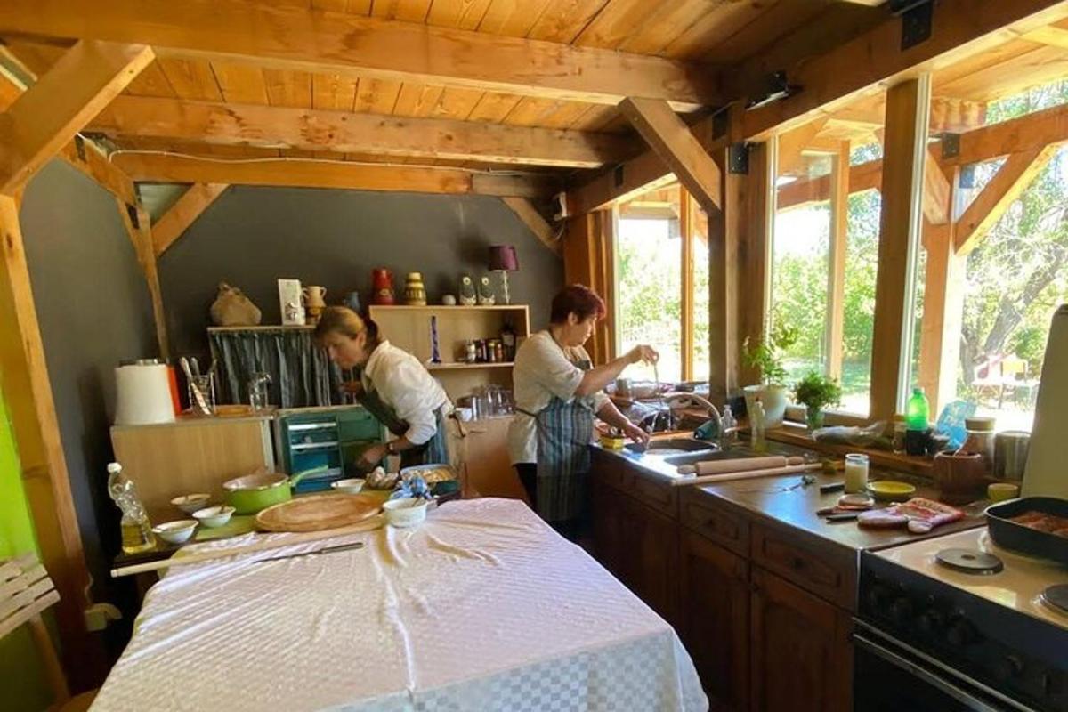 dva lidé stojící v kuchyni a připravující jídlo