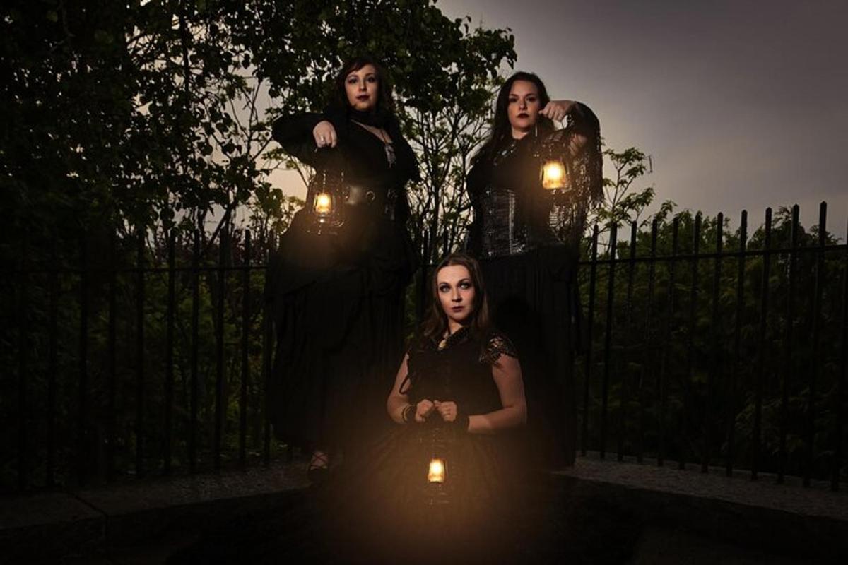 four women standing in front of a fence with lights