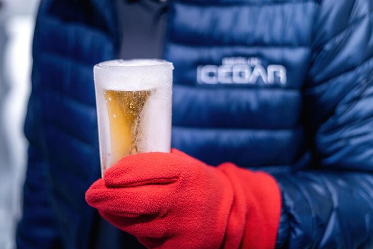 osoba držící sklenici piva s červenou rukavicí