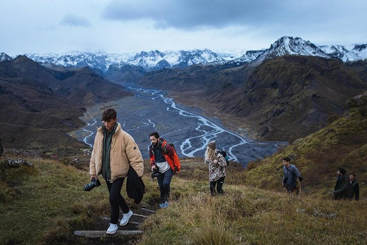 um grupo de pessoas caminhando em uma colina com vista para um rio