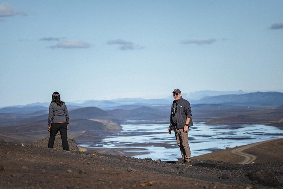 Dos personas de pie en la cima de una colina con vistas a un río.