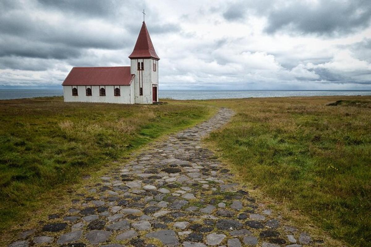 uma igreja em um campo com uma estrada de cascalho