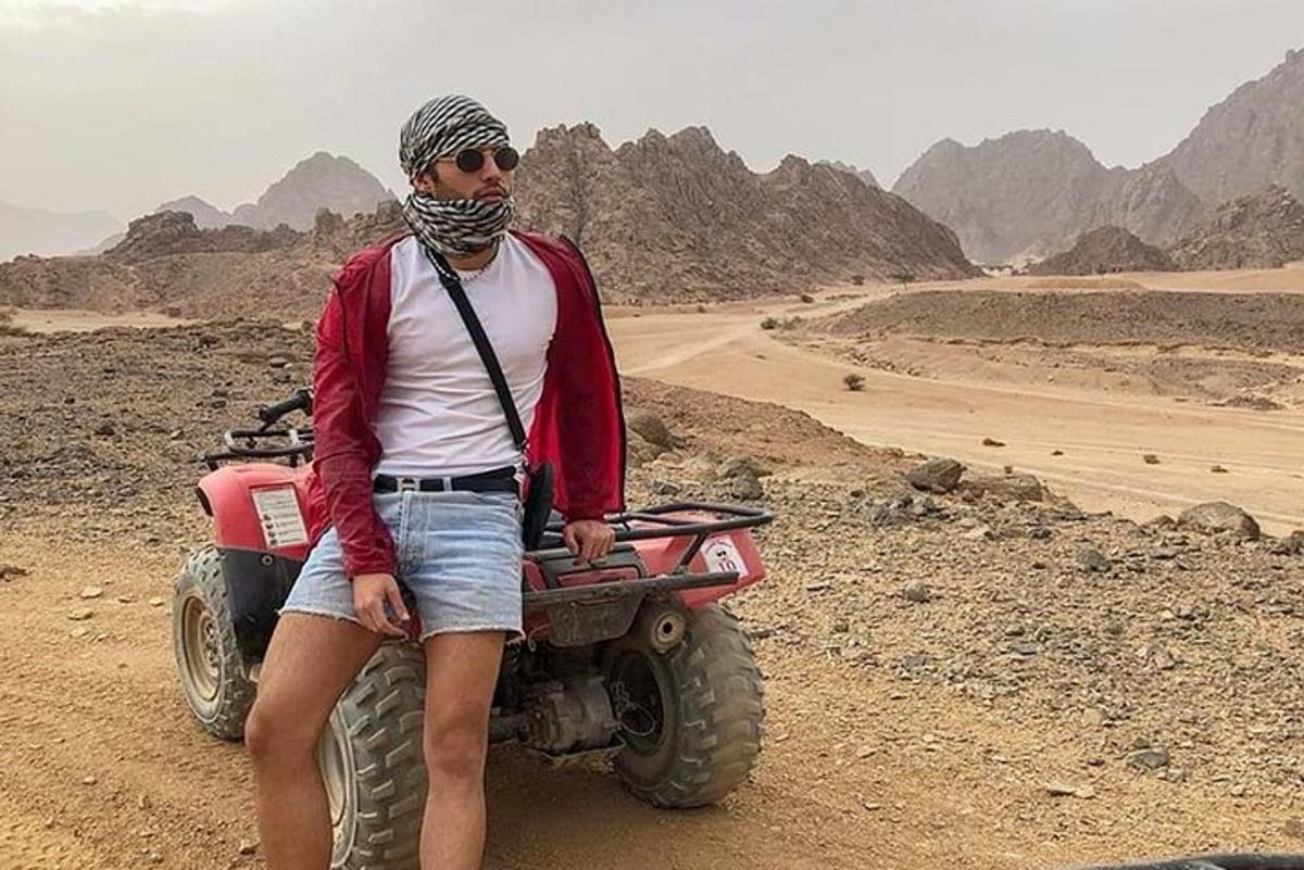 a man standing next to a wheeler in the desert