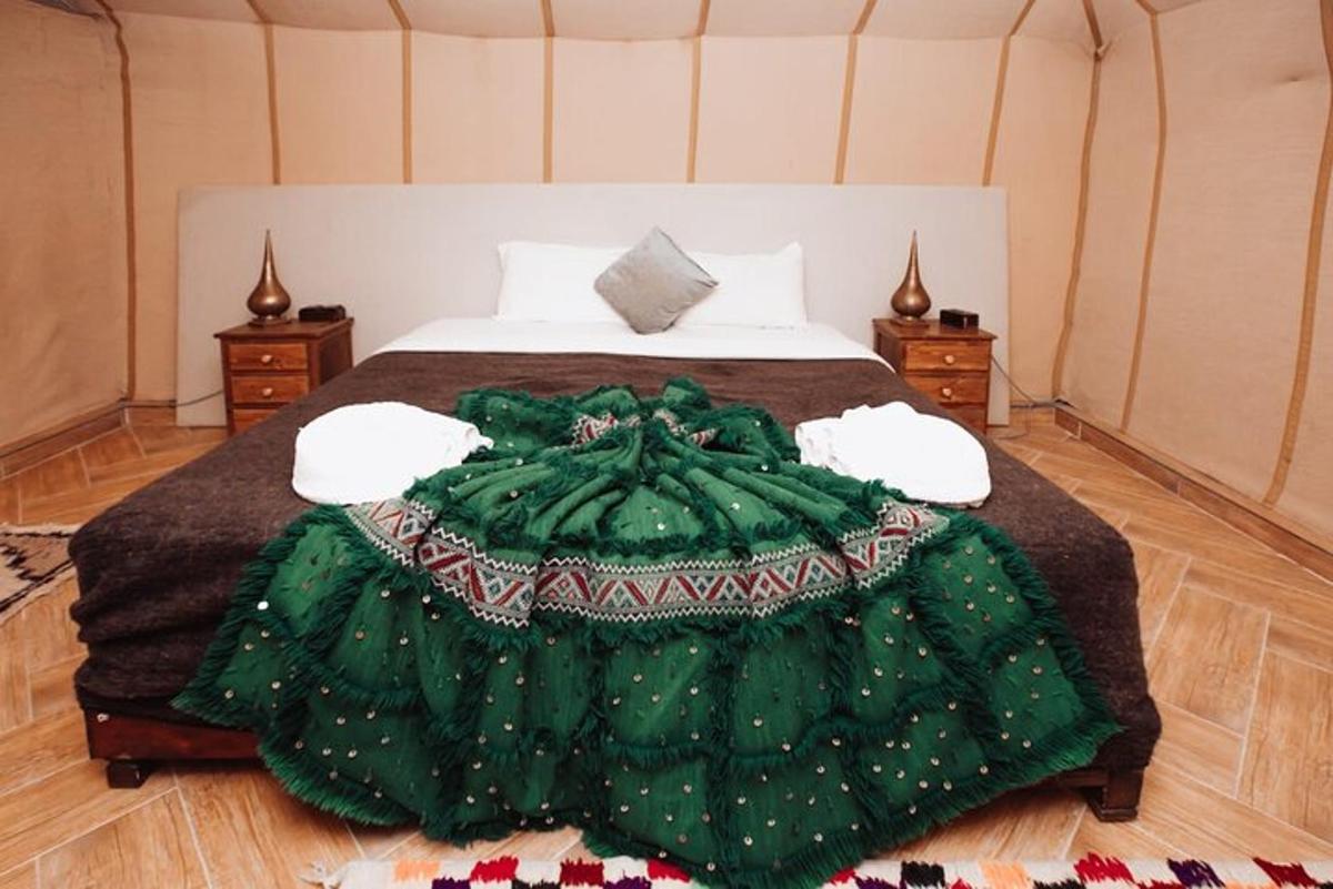 Un dormitorio con una cama verde con dos mesitas de noche.