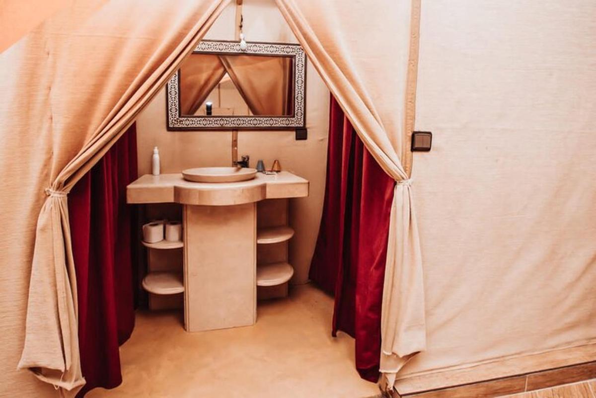Un baño con lavabo y espejo en una tienda de campaña.