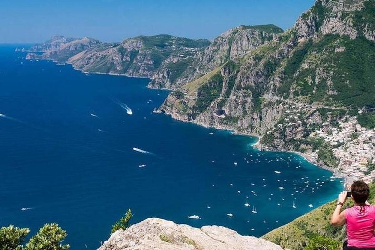 seorang wanita berdiri di tebing sambil mengambil gambar laut